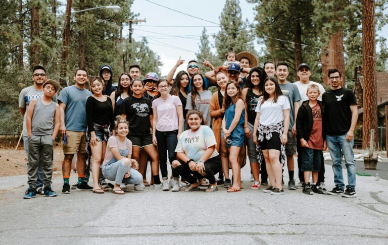 Group photo of community members posing on street near woods