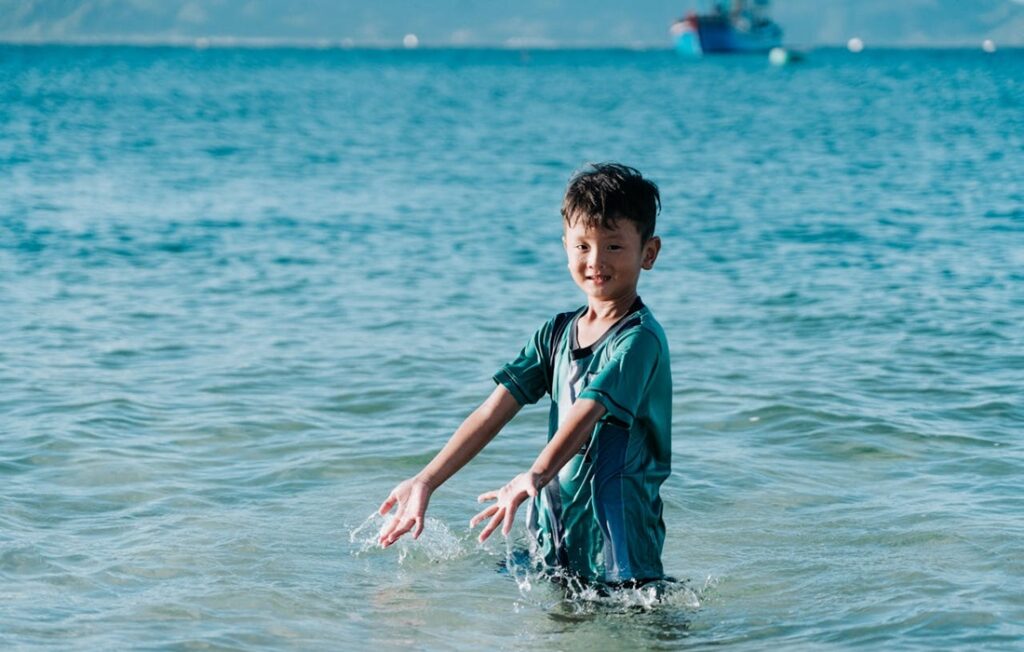 young boy splashes in ocean water